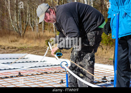 Ronneby, Svezia - Marzo 26, 2016: falegname misurare alcuni tubi in plastica per riscaldamento a pavimento con un righello di legno su una constructio Foto Stock