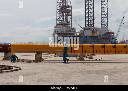 Uomini al lavoro di fronte ad un mucchio di rig Foto Stock