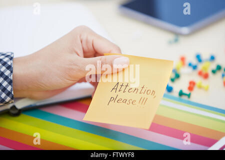 Mano umana tenendo nota adesiva con attenzione il testo Foto Stock