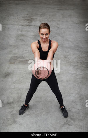 Giovane donna di sollevare un peso kettlebell in palestra Foto Stock