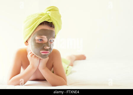 Ritratto di una ragazza con una maschera facciale e asciugamano turbante sul suo capo Foto Stock