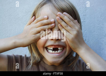 Ragazzo con gap sorriso dentato con le mani che coprono gli occhi Foto Stock