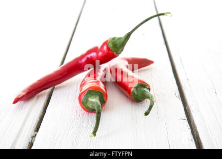 3 peperoncino rosso su bianco rustico sfondo di legno Foto Stock