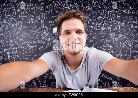 Hipster studente facendo prendendo selfie contro una grande lavagna Foto Stock