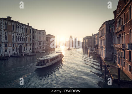 Misty sunrise sul Canal Grande a Venezia con un traghetto verso la Basilica di Santa Maria della Salute Foto Stock