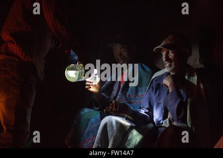 Nord Shewa, Etiopia, 2013: gli agricoltori godetevi un bicchiere di fatti in casa a base di araki attorno a un fuoco. Foto Stock