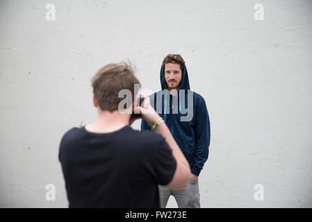 Scattare le foto di un tizio con hoddie davanti ad un muro bianco Foto Stock