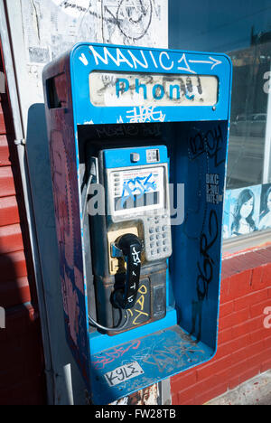 Una cabina telefonica pubblica vandalizzata e trascurata coperta da graffiti in un angolo della strada nel quartiere di Kensington Market di Toronto, Canada Foto Stock