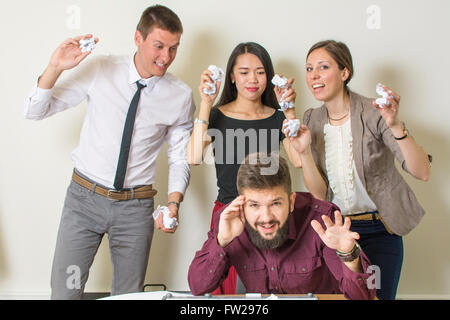 Persone che lanciano sui documenti di un collega in ufficio Foto Stock