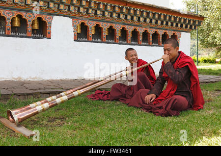 I monaci tibetani giocando le corna, Chimi tempio, Punakha distretto, Bhutan Foto Stock