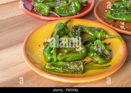 Padron grigliate peperoni con il sale e il pepe su piastre colorate Foto Stock