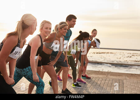 L'inizio di una maratona, gli atleti in piedi alla linea di partenza. Esecuzione di concorrenza sul lungomare. Foto Stock