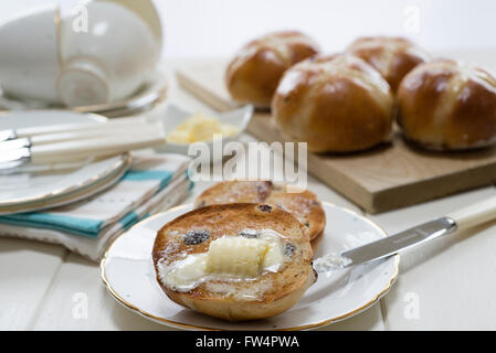 Tostato caldo in casa croce panini con burro di fusione collocato su una crema un tavolo di legno. Foto Stock