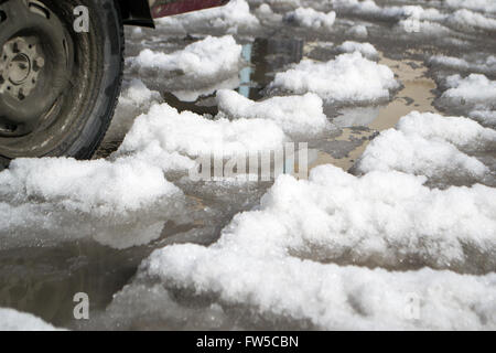 Neve fusa allagato la strada. Pozza closeup. Foto Stock