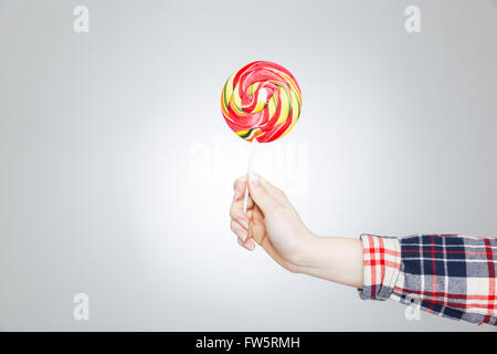Primo piano della mano nella camicia a scacchi azienda lecca-lecca colorati Foto Stock
