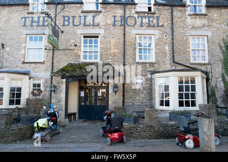 Tre mobility scooter parcheggiata fuori il Bull Hotel in High Street in Fairford, Gloucestershire, Regno Unito Foto Stock