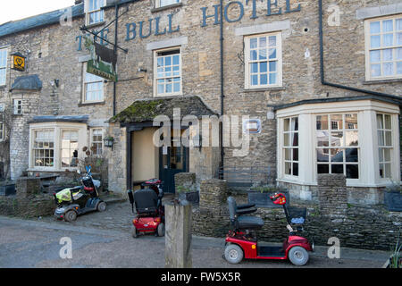 Tre mobility scooter parcheggiata fuori il Bull Hotel in High Street in Fairford, Gloucestershire, Regno Unito Foto Stock