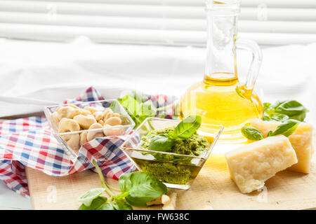 Pesto di basilico foglie di basilico fresco formaggio parmigiano olio di oliva e di semi di anacardi sulla luce sullo sfondo di legno Foto Stock