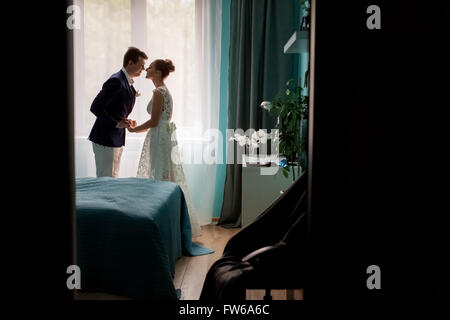 Foto piena di sagoma scura della coppia di sposi novelli sposi kissing nella finestra Interno camere da letto su sfondo al coperto, Foto Stock