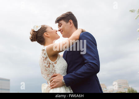 Ritratto di giovane felice bella sposi guardare a ogni altro, avvolgente e sorriso sul cielo blu sullo sfondo Foto Stock