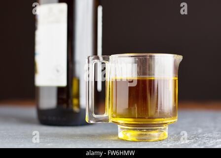 Una piccola caraffa di vetro dell' olio d' oliva nella parte anteriore di una bottiglia. Foto Stock