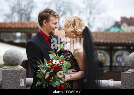 Abbracciando e sorridenti sposi con bouquet outdoor Foto Stock