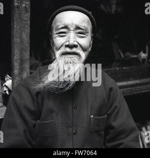 Degli anni Cinquanta, storico personaggio ritratto da J Allan denaro.di un Hong Kong uomo con una lunga barba wispy e indossando i vestiti tradizionali. Foto Stock