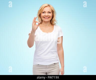 Donna felice in t-shirt bianco mostra segno OK con la mano Foto Stock