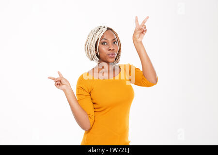 Giocoso eccitato americano africano giovane donna con trecce che mostra segni di pace su sfondo bianco Foto Stock