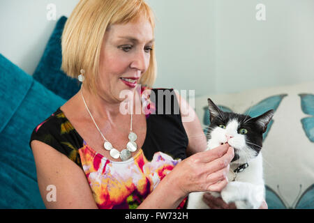 Donna alimentando il suo gatto di casa con la tratta Foto Stock