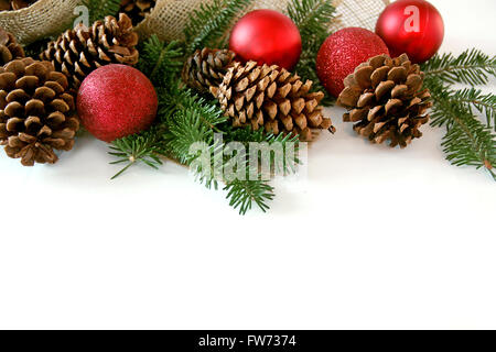 Red Addobbi Natale, pigne, rami di sempreverdi e tessuto di tela sono la creazione di una cornice, isolata su una schermata bianca vuota Foto Stock