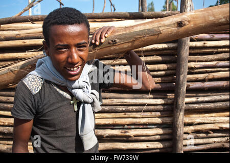 Giovane uomo che porta un albero di eucalipto tronco sulle sue spalle (Etiopia) Foto Stock