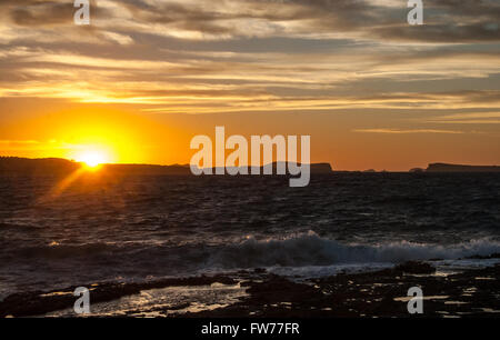 Golden Sunset dietro Conejera Isole. Increspato mare Baleari zangole onde su scogli lungo la riva. Visualizzare dietro Cafe del mar a Ibiza. Foto Stock