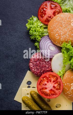 Dark restaurant menu, burger ingredienti e copia dello spazio. In ardesia scura dall'alto. Foto Stock