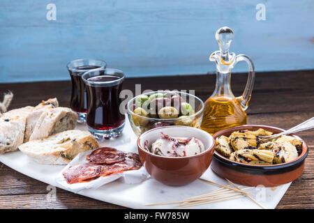 Tapas tradizionali sulla scheda di marmo con un bicchiere di vino rosso Foto Stock