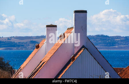 Gables contro il blu del mare, con i camini di bianco e il tetto di tegole. Il campionamento del danese tipico o scandinava di tradizioni edilizie Foto Stock