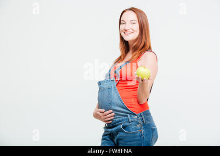 Sorridente donna incinta azienda apple isolato su uno sfondo bianco Foto Stock