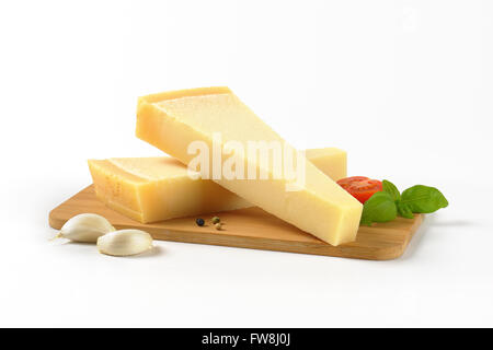 Due spicchi di parmigiano fresco e guarnire sul tagliere di legno Foto Stock