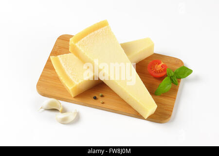 Due spicchi di parmigiano fresco e guarnire sul tagliere di legno Foto Stock