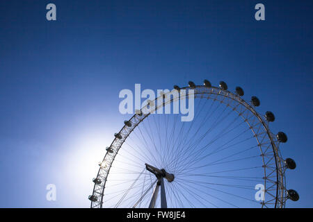 Il London eye retroilluminati da sole in un profondo cielo blu a Londra la città capitale del Regno Unito. I baccelli dove i viaggiatori alzarsi e sedersi per il viaggio può essere chiaramente visto sillhouetted contro il sole brillante. Nella parte superiore di una magnifica vista di Londra può essere visto da est a ovest e a nord di Sourth. Foto Stock