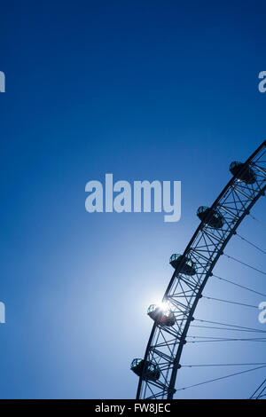 Il London eye retroilluminati da sole in un profondo cielo blu a Londra la città capitale del Regno Unito. I baccelli dove i viaggiatori alzarsi e sedersi per il viaggio può essere chiaramente visto sillhouetted contro il sole brillante. Nella parte superiore di una magnifica vista di Londra può essere visto da est a ovest e a nord di Sourth. Foto Stock