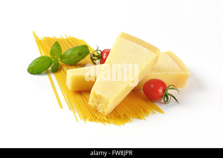 Due spicchi di parmigiano fresco, verdure e spaghetti su sfondo bianco Foto Stock