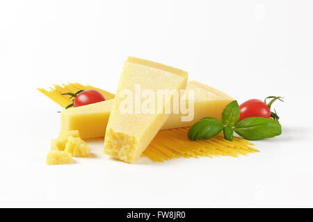 Due spicchi di parmigiano fresco, verdure e spaghetti su sfondo bianco Foto Stock