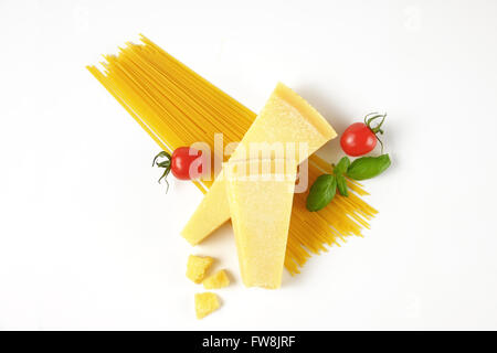 Due spicchi di parmigiano fresco, verdure e spaghetti su sfondo bianco Foto Stock