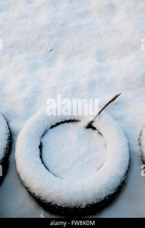 Vecchi pneumatici da auto che vengono utilizzati come rende postamento piantatrici per vegeatbles e fiori rendono i modelli astratti nella neve come essi sono quasi coperto e perso nella spessa coltre bianca. Foto Stock