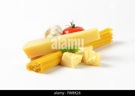 Parmigiano fresco, verdure guarnire e fascio di materie spaghetti su sfondo bianco Foto Stock