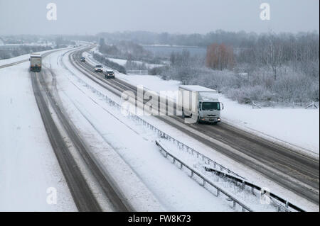 Una vista della A419 / A417 by pass la coperta di neve con i veicoli che viaggiano molto lentamente nella pericolosa condizioni stradali, nella foto dopo un pesante nevicata invernale la strada che teste attraverso il cuore di Cotswolds nel Regno Unito è a malapena praticabile in questi unusally cattive condizioni per viaggiare. Foto Stock