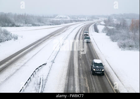 Una vista della A419 / A417 by pass la coperta di neve con i veicoli che viaggiano molto lentamente nella pericolosa condizioni stradali, nella foto dopo un pesante nevicata invernale la strada che teste attraverso il cuore di Cotswolds nel Regno Unito è a malapena praticabile in questi unusally cattive condizioni per viaggiare. Foto Stock