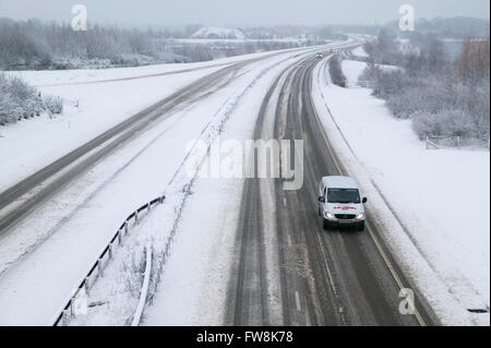 Una vista della A419 / A417 by pass la coperta di neve con i veicoli che viaggiano molto lentamente nella pericolosa condizioni stradali, nella foto dopo un pesante nevicata invernale la strada che teste attraverso il cuore di Cotswolds nel Regno Unito è a malapena praticabile in questi unusally cattive condizioni per viaggiare. Foto Stock