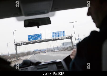 Una vista attraverso la parte anteriore winodw o il parabrezza di un automobile che viaggia lungo la M5 nell'soouth ovest del Regno Unito. Come il veicolo viaggia lungo l'autostrada l'overhead gantry segni può essere chiaramente visto che indicano i percorsi a Londra, il Galles, le Midlands e altre destinazioni NEL REGNO UNITO. Foto Stock